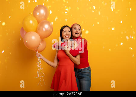 Mädchen bereit für eine Party mit Luftballons. Freudige ein Glück Ausdruck. Gelber Hintergrund Stockfoto