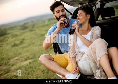 Liebevolle junge Paar sitzen im Auto trank während der Reise in der Natur Stockfoto