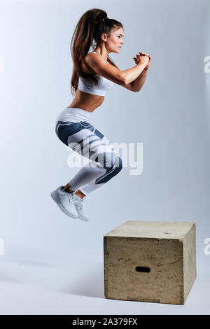 Starke Frau, springen auf die Box motiviert, Krafttraining, Freizeit, Freizeitbeschäftigung, volle Länge Seitenansicht phot, isoliert weißer Hintergrund, Studio shot Stockfoto
