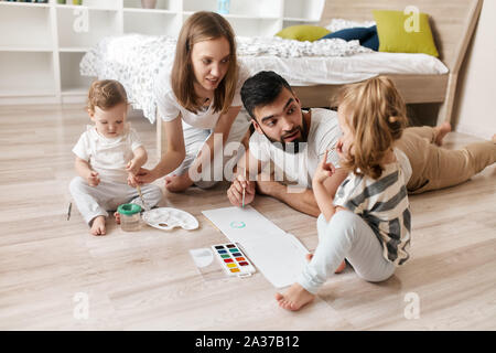 Fröhliche Eltern lehren ihre Kinder zu zeichnen. Bildung. Lifestyle, Freizeit, Freizeit Stockfoto