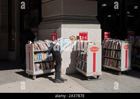 Eine junge Dame sucht die Bücher auf den Verkauf außerhalb der Faser Buchhandlung am Broadway in Greenwich Village, Manhattan, New York City. Stockfoto