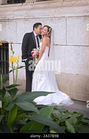 Eine Asiatische Paare teilen ein Lachen, während für Hochzeit Fotos außerhalb der wichtigsten Zweig der New York Library in Midtown Manhattan, New York City posieren. Stockfoto