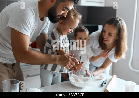 Bärtige Daddy und lächelnd schöne Mutter lehren ihre Kinder Teig zu rühren, Nahaufnahme, Seite, Ansicht Foto Stockfoto