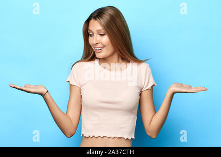 Freundliche attraktive lächelnden jungen Frau mit beiden Händen open Palms, Präsentation, Werbung etwas. Balance Konzept. Frau, Wahl, Isola Stockfoto