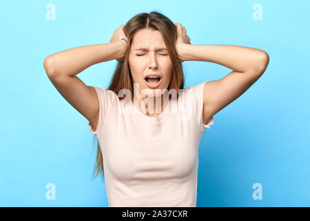 Wütend, traurig, unglücklich, nervösen Frau schreien berühren den Kopf frustriert. bis Foto schliessen. Gesichtsausdruck, Reaktion, Mädchen hat schreckliche Kopfschmerzen. heilen Stockfoto