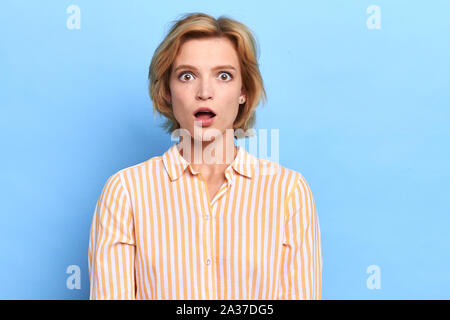 Schockiert blond emotionale Angst Frau mit ihren Mund öffnete, blau, Nahaufnahme, Porträt isoliert, Studio erschossen. Gesichtsausdruck und Reaktion Stockfoto