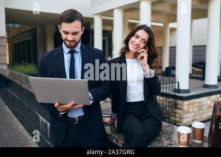 Junge intelligente Menschen die Teilnahme an der Webkonferenz, während Frau einen Anruf tätigen Stockfoto