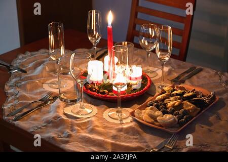 Schön gedeckten Tisch für die Weihnachtsferien. Süßigkeiten, Kerzen und Weihnachtsschmuck dekoriert Home am Heiligabend. Stockfoto