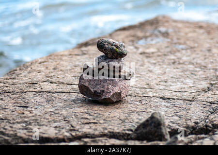 Die Steine der Pyramide auf Sand symbolisiert zen, Harmonie, Balance. Meer im Hintergrund. Stockfoto