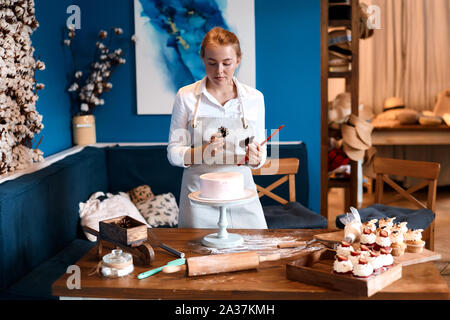 Kreativ Konditorei dekorieren Kuchen in der Küche mit moderner Inneneinrichtung. bis Foto schliessen. Kunst, Hobby, Interesse Stockfoto