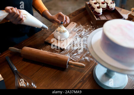 Talentierten Küchenchef konzentrierte sich auf Cooking Cup Kuchen zu verkaufen, bis 7/8 schließen Foto Stockfoto