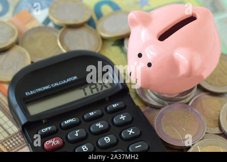 Sparschwein und Rechner mit dem Wort Steuer auf Geld-Konzept der Einsparung von Kosten und Steuern zahlen Stockfoto