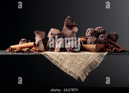 Schokolade Trüffel mit Brocken von Schokolade und Gewürzen. Schokolade, Zimt und Anis auf einem dunklen Hintergrund. Kopieren Sie Platz. Stockfoto