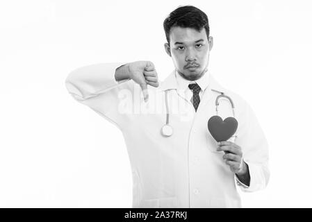 Studio shot junger asiatischer Mann Arzt halten roten Herzen und geben Daumen nach unten Stockfoto