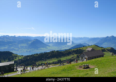 Panoramablick auf die Landschaft aus Wiesen, Berge mit schneebedeckten Gipfeln und den Vierwaldstättersee im Hintergrund von der Oberseite der Rigi Kulm, Mount Rig Stockfoto