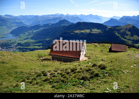 Panoramablick auf die Landschaft aus Wiesen, Berge und verschneite Berggipfel mit zwei kleinen Häusern von der Oberseite der Rigi Kulm die Rigi in Switzerla Stockfoto