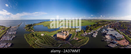 Breite Antenne Panoramablick auf das Schloss Muiderslot in Bergen in der Nähe von Amsterdams und seiner üppigen Gärten am IJsselmeer mit umliegenden Verankerung Stockfoto