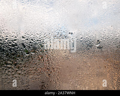 Nass und regnerisch, eine Nahaufnahme von Wasser dropplets auf einer Fensterscheibe. Ich wurde durch die Farben, Muster und Struktur fasziniert. Stockfoto