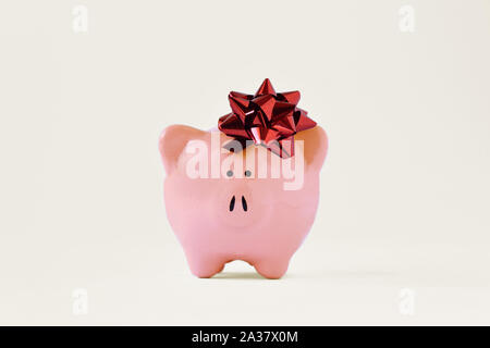 Piggy Bank mit roter Schleife - Begriff der Weg Geld Bonus Stockfoto