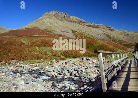 Die Wainwright Great Gable von einer hölzernen Fußgängerbrücke auf dem Mose trat Wanderweg in Wasdale, Nationalpark Lake District, Cumbria, England, UK. Stockfoto