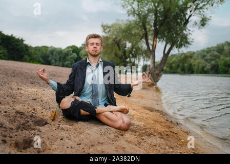 Büro am Strand zu sitzen im Yoga pose Stockfoto