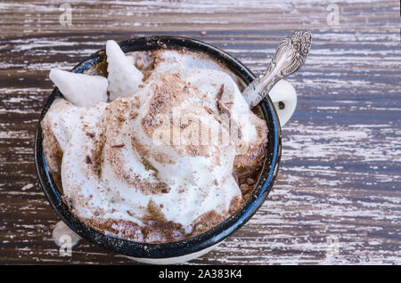 Emaille Tasse heiße Schokolade Kakao mit Schlagsahne und Christbaum Bonbons auf hölzernen Tisch Hintergrund. Weihnachten trinken Konzept. Köstlich kalt Wir Stockfoto