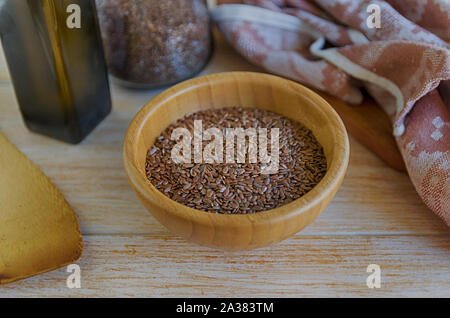 Brauner Leinsamen in Houten und Leinsamenöl auf einem rustikalen Tisch. Superfood: Leinsamen sind reich an Omega-3-Fettsäuren, essentiell für gute Gesundheit. Stockfoto