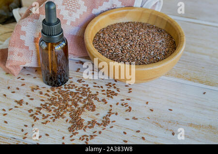 Brauner Leinsamen in Houten und Leinsamenöl auf einem rustikalen Tisch. Superfood: Leinsamen sind reich an Omega-3-Fettsäuren, essentiell für gute Gesundheit. Stockfoto