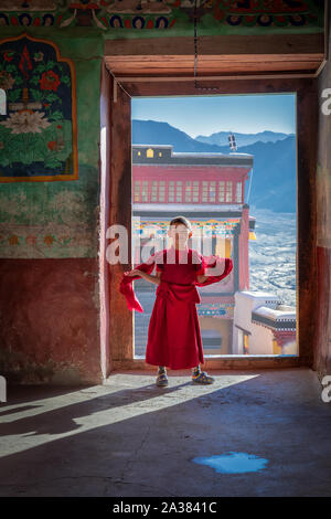 Ein junger Mönch gehen durch eine Tür an der Thiksey Kloster, Ladakh, Jammu und Kaschmir, Indien Stockfoto