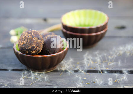 Rohe Trüffel Kugeln aus Mandeln, Kakao Butter, medjool Termine und Johannisbrot. Vegane Schokolade Dessert in Keramik Schüssel auf den Holztisch. Gesunde Rohstoffe fo Stockfoto