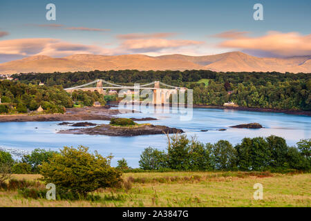 Ein Blick auf die Menai Bridge von Anglesey über die Menai Strait in Richtung Wales Festland und die Bergkette des Snowdonia National Park. Stockfoto