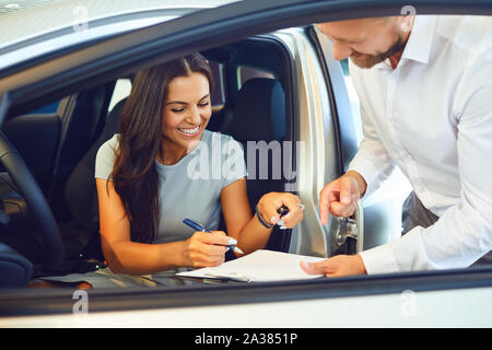 Eine junge Frau ein Auto kauft in einem Autohaus. Stockfoto