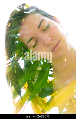 Doppelte Belichtung Porträt einer jungen, entspannt die natürliche Schönheit mit geneigter Kopf seitwärts und lange braune Haare mit grünen tropischen Blätter auf einem kombiniert wird. Stockfoto