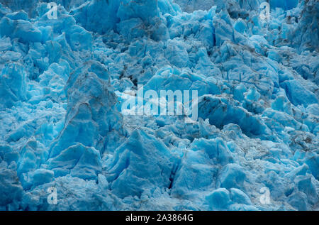 Große Eisblöcke des nordwestlichen Gletschers, intensiv blau gefärbt, teilweise dünn mit Staub bedeckt, an einem bewölkten Sommertag. Stockfoto