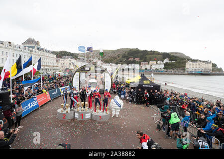 Llandudno, Wales, UK. 6. Okt 2019. Nicolas Gilsoul, Thierry Neuville, Martin Jarveoja, Ott Tanak, Sebastien Ogier, Julien Ingrassia feiern auf dem Podium des GB Welsh Rally 2019 Credit: Jason Richardson/Alamy leben Nachrichten Stockfoto