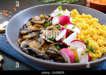 Linsen Porridge mit Champignons, Radieschen in einer Schüssel auf einem dunklen Hintergrund. Diätetische, Lean Menü. Vegetarisches Gericht Stockfoto