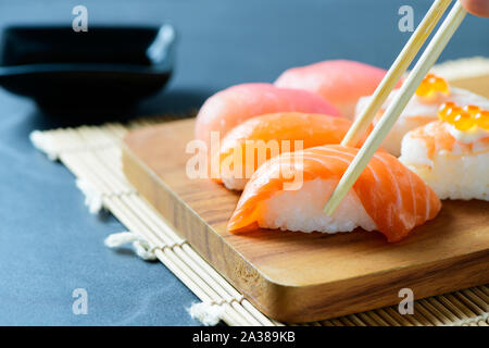 Lachs nigiri Sushi mit Stäbchen mit Sashimi Sushi am Schwarzen Stein Hintergrund gesetzt, japanische Küche Stockfoto