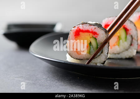 Sushi Rollen (Gemüse, Inari und Crab Sticks) mit Stäbchen, populäres japanisches Essen Stockfoto