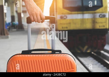 Frau ziehen orange Koffer Gepäck Tasche, Wandern im Bahnhof. Travel Concept. Stockfoto