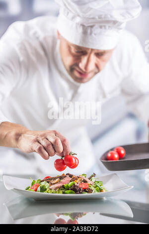 Koch in der Küche des Hotel oder Restaurant schmückt das Essen kurz vor dem Servieren. Stockfoto