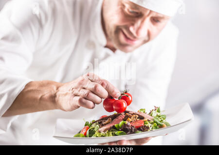 Koch in der Küche des Hotel oder Restaurant schmückt das Essen kurz vor dem Servieren. Stockfoto