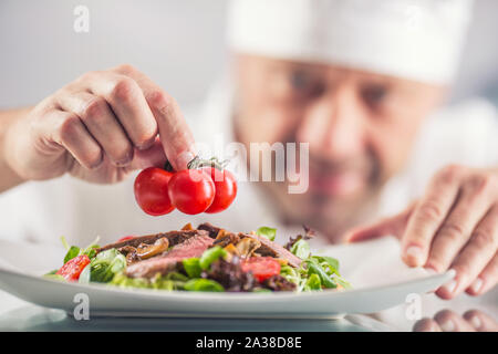 Koch in der Küche des Hotel oder Restaurant schmückt das Essen kurz vor dem Servieren. Stockfoto