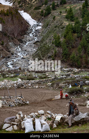 Menschen Reinigung Boden für den Anbau. Im Hintergrund Gletscherbach in Kinnaur Kailash, verbindet die Baspa River. Stockfoto