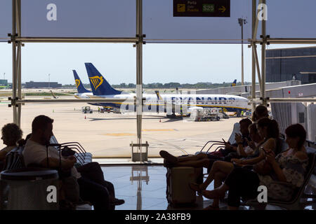 Barcelona, Spanien - 11. August 2019: die Passagiere der Boarding Gate am Flughafen warten, mit Ryanair Flugzeug im Hintergrund Stockfoto