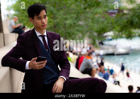 Junge Unternehmer am Riverwalk Holding sein Handy, Chicago, Illinois, United States Stockfoto