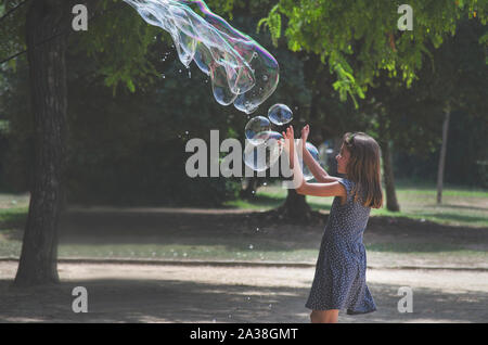 Mädchen spielen mit riesigen Blasen in einem Park, Frankreich Stockfoto