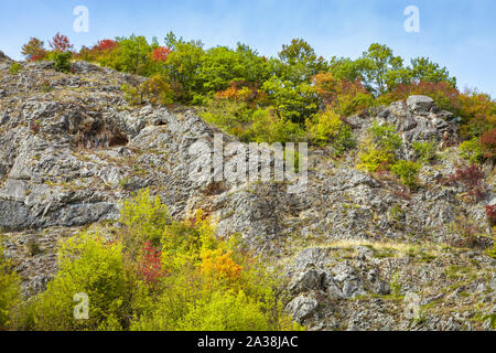 Lebendige Farben des Herbstes in einem Wald auf eine felsige Klippe in eine enge Schlucht in Serbien, mit roten, grünen und gelben Bäume unter einem blauen Himmel Stockfoto