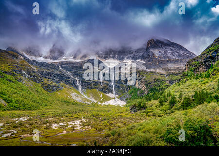 Gebirge gegen üppiges Grün und dramatische Wolken im Herbst in yading Naturschutzgebiet, China Stockfoto