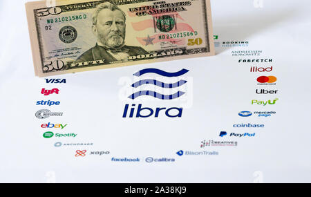 Die Libra Logo auf dem Papier Broschüre und US Dollar Banknoten. Illustrativ für globale's Facebook Währung Waage, die Gegensätze der Fiat money Stockfoto