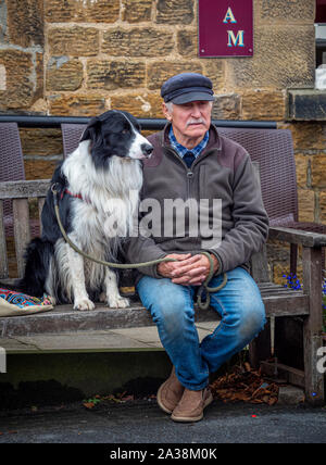 Mann mit Hund saß auf Holztisch, Masham Schafe Fair Stockfoto